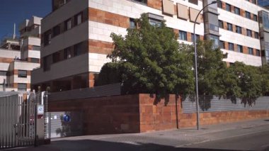 Gündüz saatlerinde manzaralı şehir sokağının önünden geçen siyah minibüslü modern konut binası.