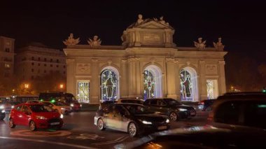 Madrid, İspanya 'daki Puerta de Alcala' nın aydınlatılmış noel süslemelerinin yanından geçen trafiğin gece görüşü