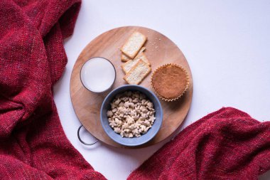 Beyaz yemek masasındaki kahvaltı menüsünün en üst görüntüsü. Kahve, süt, mısır gevreği, elma, kraker ve çörekler yukarıdan beyaz masa manzaralı..