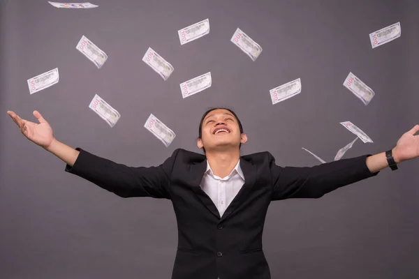 A young business man celebrating his achievement and throwing a lot of money to air.