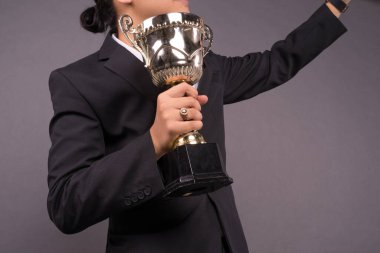 Elinde altın bir kupa olan genç bir iş adamı arşivini kutluyor. Yakın çekim.
