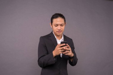 Akıllı telefon kullanırken gülümseyen genç bir iş adamı..