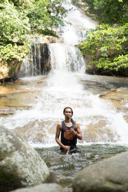 22 Eylül 2020, Şah Alam Selangor.Şelale havuzunda bir genç. Erkek yürüyüşçü yağmur ormanı şelalesinin manzarasının keyfini çıkarıyor..