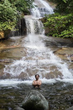 22 Eylül 2020, Şah Alam Selangor.Şelale havuzunda bir genç. Erkek yürüyüşçü yağmur ormanı şelalesinin manzarasının keyfini çıkarıyor..