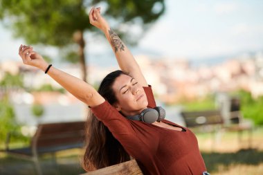 Esmer kız parkta kollarını açıyor.