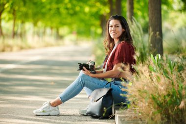 Rahat öğrenci elinde kamerayla parkta oturdu.