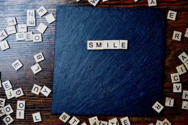 Tahta taşın üzerine ahşap harflerle yazılmış gülümseme mesajı