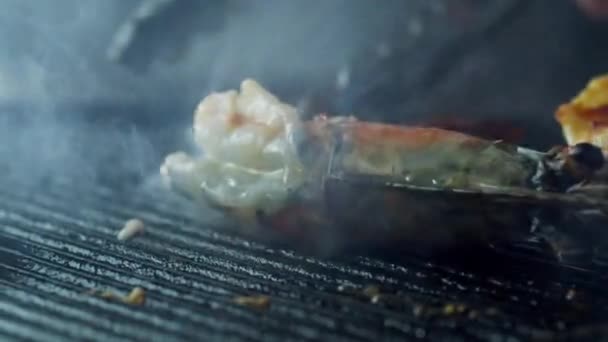 Щипцы переворачивает креветки, которые жарятся с травами и чесноком — стоковое видео