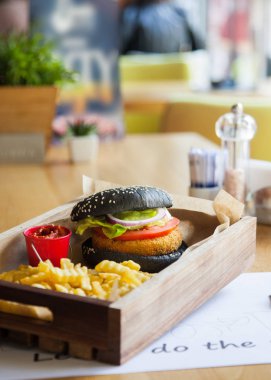 Siyah renkli küçük ağız sulandıran, lezzetli burger ahşap tepsi üzerinde kırmızı ketçap sos ile.