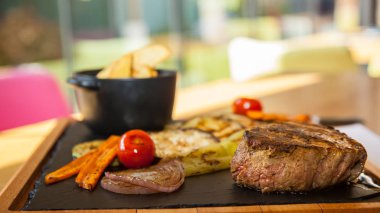 Sığır eti biftek fırında patates ve restourant ahşap bir tabakta sebze ile servis.