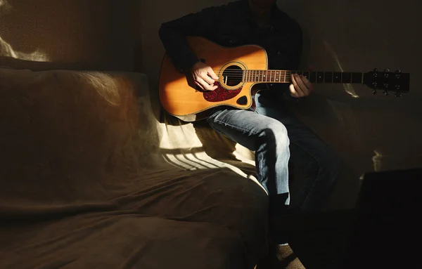 Akustik gitarlı ve şapkalı bir adam, karantina sırasında ve koronavirüs yüzünden kendini tecrit etmeye zorlanırken dizüstü bilgisayarı önünde seyirciler için canlı yayında oynuyor. Ev kavramından çalış. 