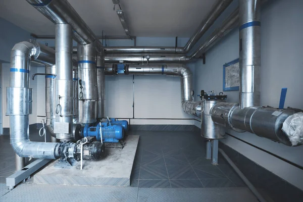 Pumps and pipes for water supply and steam installed in the boiler room. Blue toning