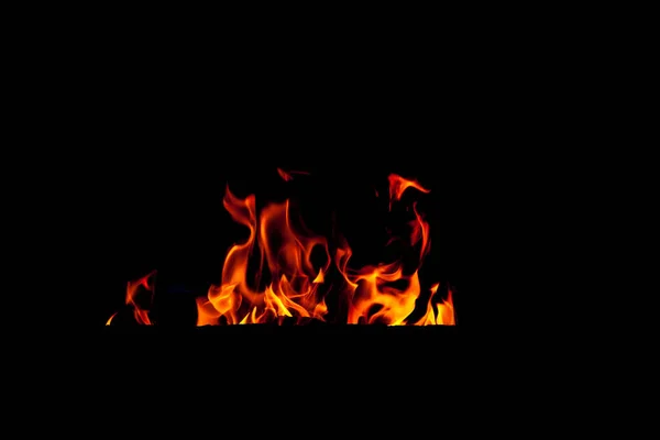 Ateş alevi siyah arka planda izole edildi. Şöminenin arka planında gerçek alev dilleri var.