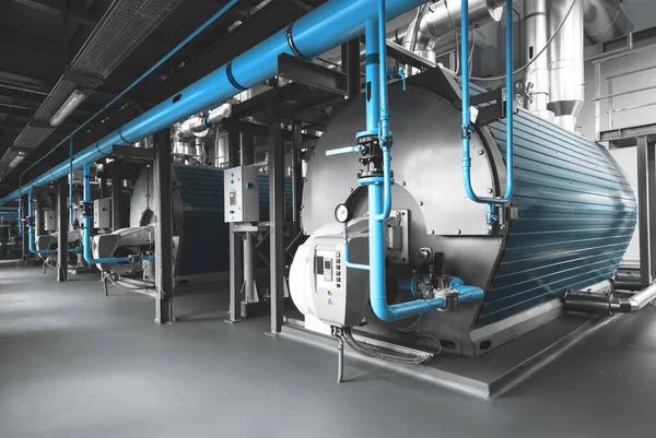 Isınma işlemi için donanımlı modern endüstriyel gaz kazan dairesi. Isıtma kazanları, boru hatları, vanalar. Mavi tonlama