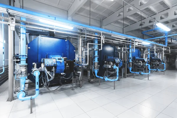 Isınma işlemi için donanımlı modern endüstriyel gaz kazan dairesi. Isıtma kazanları, boru hatları, vanalar. Mavi tonlama