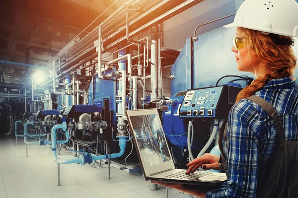 Dizüstü bilgisayarlı mühendis kadın modern endüstriyel gaz kazan dairesini inceliyor. Isıtma kazanları, boru hatları, vanalar. Karışık ortam