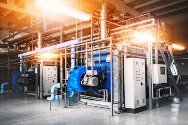 Kazan dairesinin içinde iki gaz kazanı, bir kontrol dolabı ve gaz ve buhar sağlamak için borular var. Üç çeyrek manzara. Lambaları açık mavi renkli.