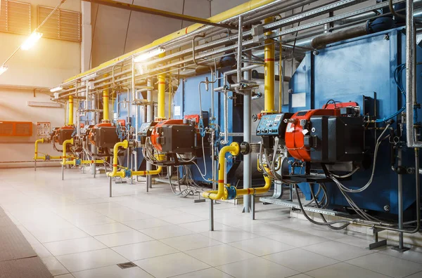 Isınma işlemi için donanımlı modern endüstriyel gaz kazan dairesi. Arka arkaya gaz kazanları, boru hatları, vanalar ısıtılıyor..
