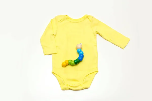 赤ちゃんの黄色のボディスーツ ラトル ペースメーカー おもちゃ 白い背景に子供服やアクセサリートップビュー — ストック写真