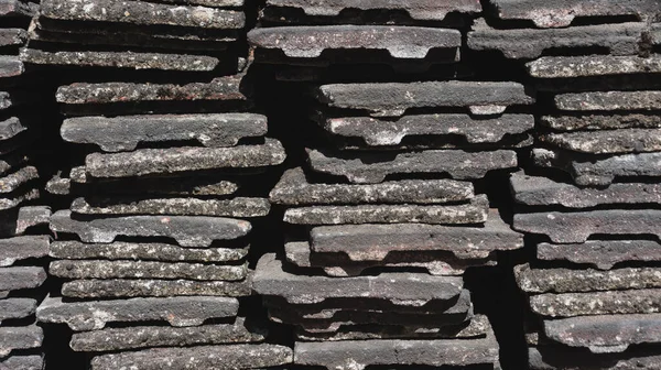 Worn concrete roof tiles stacked into piles