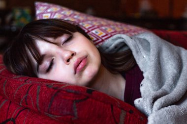 Güzel kız kanepede huzur içinde uyuyor.