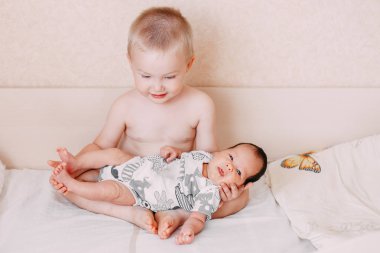 küçük kardeşi yatakta ev aile kavramı aşk, onun elinde tutan yaşlı küçük sarışın bebek kardeşi çocuk