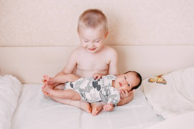 küçük kardeşi yatakta ev aile kavramı aşk, onun elinde tutan yaşlı küçük sarışın bebek kardeşi çocuk