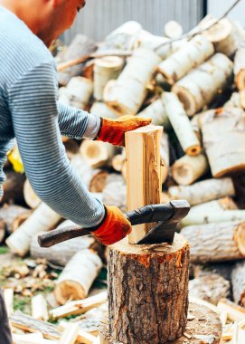 Kütüğün üzerinde talaşla uçan iki tahta parçasının ayrıntıları. Adam antika baltayla odun kesiyor. Donmuş an.