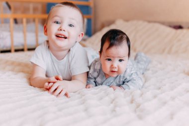 Sevimli küçük dört aylık bebek kız ve abisi evde yatak yatak, yorgan altında oynarken, mutlu bir şekilde gülümseyerek