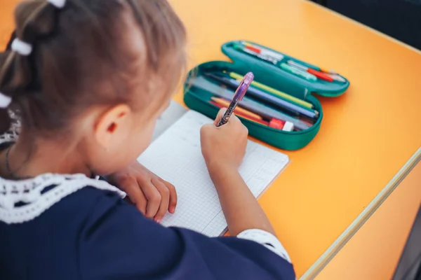 Skolflicka skriva på schoolbook i hennes klassrum — Stockfoto