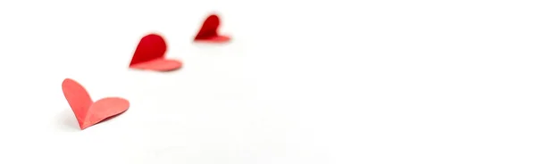 Три червоні паперові серця ізольовані на білому тлі, крупним планом зосереджені на найближчому довгому серці — стокове фото