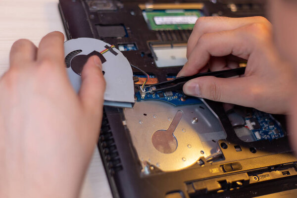 Asian laptop repair technician screw in a cooling fan in a laptop, which used to cool the laptop down while it's working