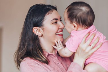 Anne ve bebek oynamak ve gülmek pembe giysiler içinde. Mutlu bir aile anneler günü