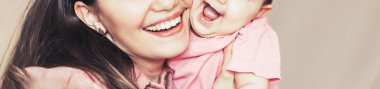 Anne ve bebek oynamak ve gülmek pembe giysiler içinde. Mutlu bir aile anneler günü uzun banner