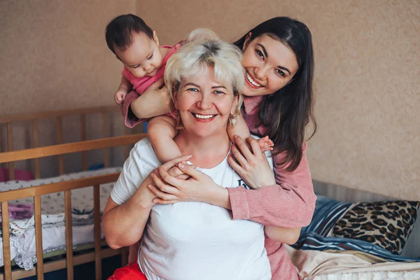 Little cute girl, her attractive young mother and charming grandmother are spending time together at home. Women\'s generation. Happy International Women\'s Day