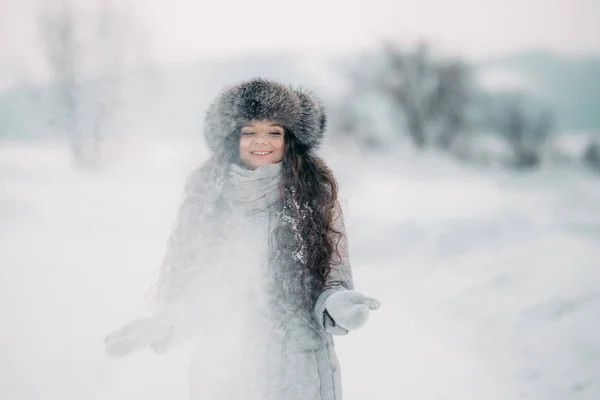 美丽的女孩在冬天皮帽微笑发挥与雪 — 图库照片