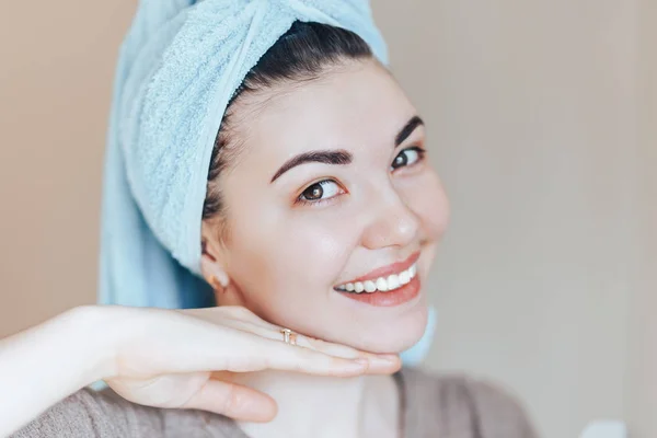 Spa mulher beleza cuidados da pele usando toalha de cabelo após o tratamento de beleza. Mulher bonita com a pele perfeita sorrindo olhando para a câmera tocar seu rosto close up foco selecionado — Fotografia de Stock