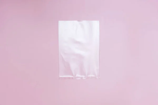 Satu tas selophane. Templat paket tas putih di tengah pink latar belakang salinan ruang flatlay — Stok Foto