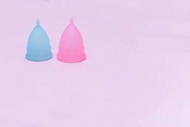 Pembe bir arka planda iki pembe ve mavi dönem menstrüel fincan. Kadın sağlığı kavramı, hijyen koruma araçları, menstrasyon, gezegenin ekoloji.