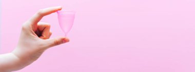 Close up of woman hand holding menstrual cup over pink background. Women health concept, zero waste alternatives clipart