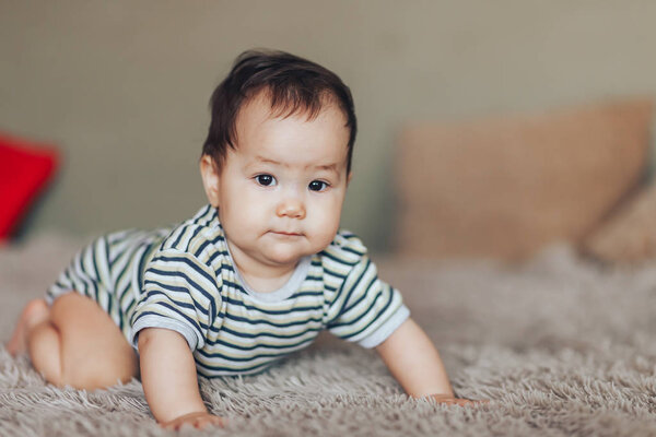 serious Baby girl sitting at bed at home. White vintage childroom. Childhood concept. looking at camera