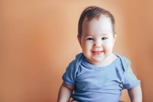 Beautiful small girl or boy with dark hair smiling on a bright orange background colour of 2019 with space for text happy smile look at camera — Stock Photo, Image