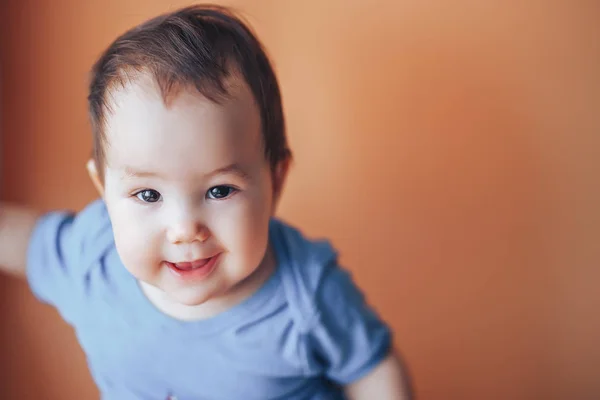 Hermosa niña o niño con el pelo oscuro sonriendo en un color de fondo naranja brillante de 2019 con espacio para el texto feliz sonrisa mira a la cámara —  Fotos de Stock