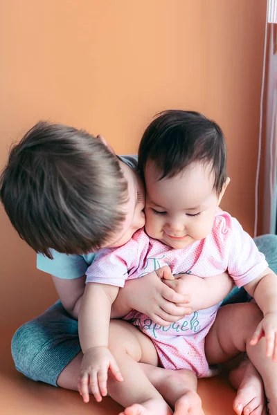 Gelukkig spelen broertje knuffels zijn zus baby, jongen en meisje omarmt kussen, concept liefde en ouderschap — Stockfoto