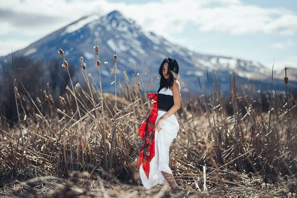 Bulutlar ile güneş ve mavi gökyüzünde dağlarda Muhteşem kadın esmer. kırmızı şal ile geleneksel giysiler — Stok fotoğraf