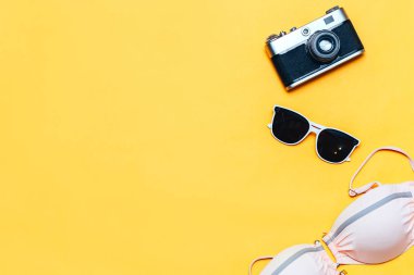 Sarı arka plan, flatlay, copyspace, vintage kamera, beyaz güneş gözlüğü ve mayo yaz aksesuarları kavramı