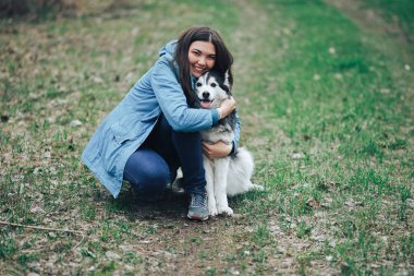 Genç bir kadın bahar ormanında yürüyüş yapmak için iri yarı köpekle oynuyor. Gülüyor eğleniyor, evcil hayvanla mutlu