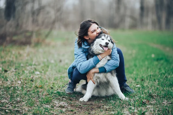 Giovane donna giocare con il cane husky per una passeggiata nella foresta primaverile. ridere divertendosi, felice con l'animale domestico — Foto Stock