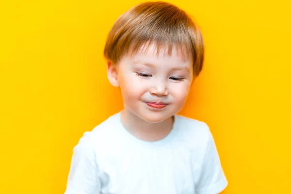 Ντροπαλό μικρό παιδί τριών ετών απομονωμένο σε κίτρινο φόντο Κοίτα κάτω και χαμογέλα — Φωτογραφία Αρχείου