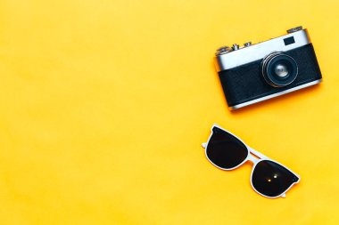 Sarı arka plan, flatlay, copyspace, vintage kamera, beyaz güneş gözlüğü ve mayo yaz aksesuarları kavramı